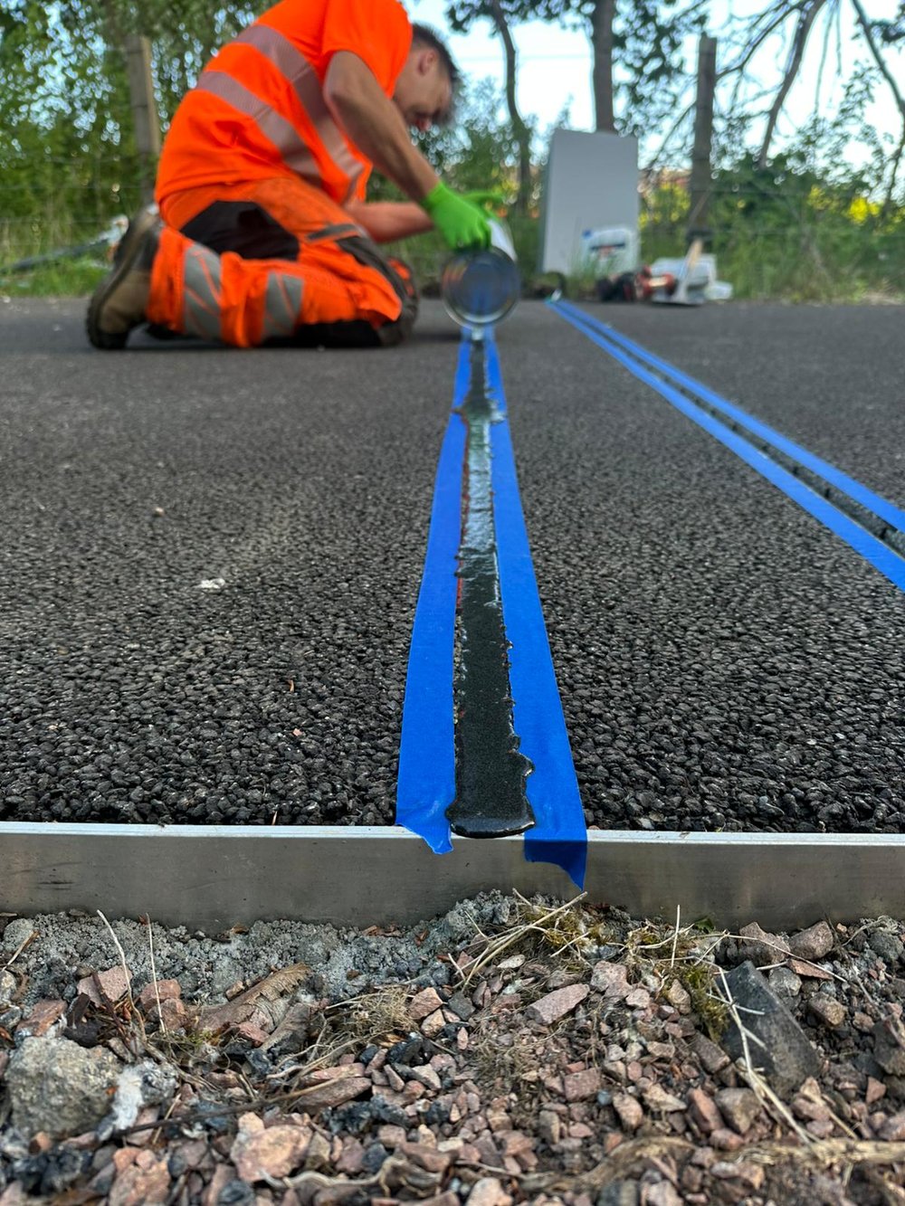 Field engineer installing an in-road sensor, sealing a saw-cut slot in the road surface