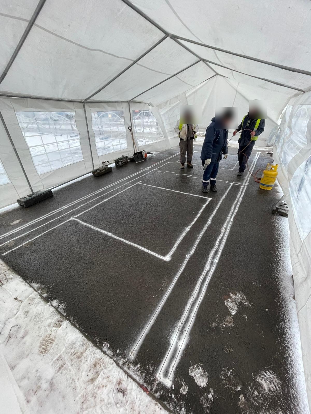 Field team installing WIM sensors inside a heated tent shelter during winter conditions